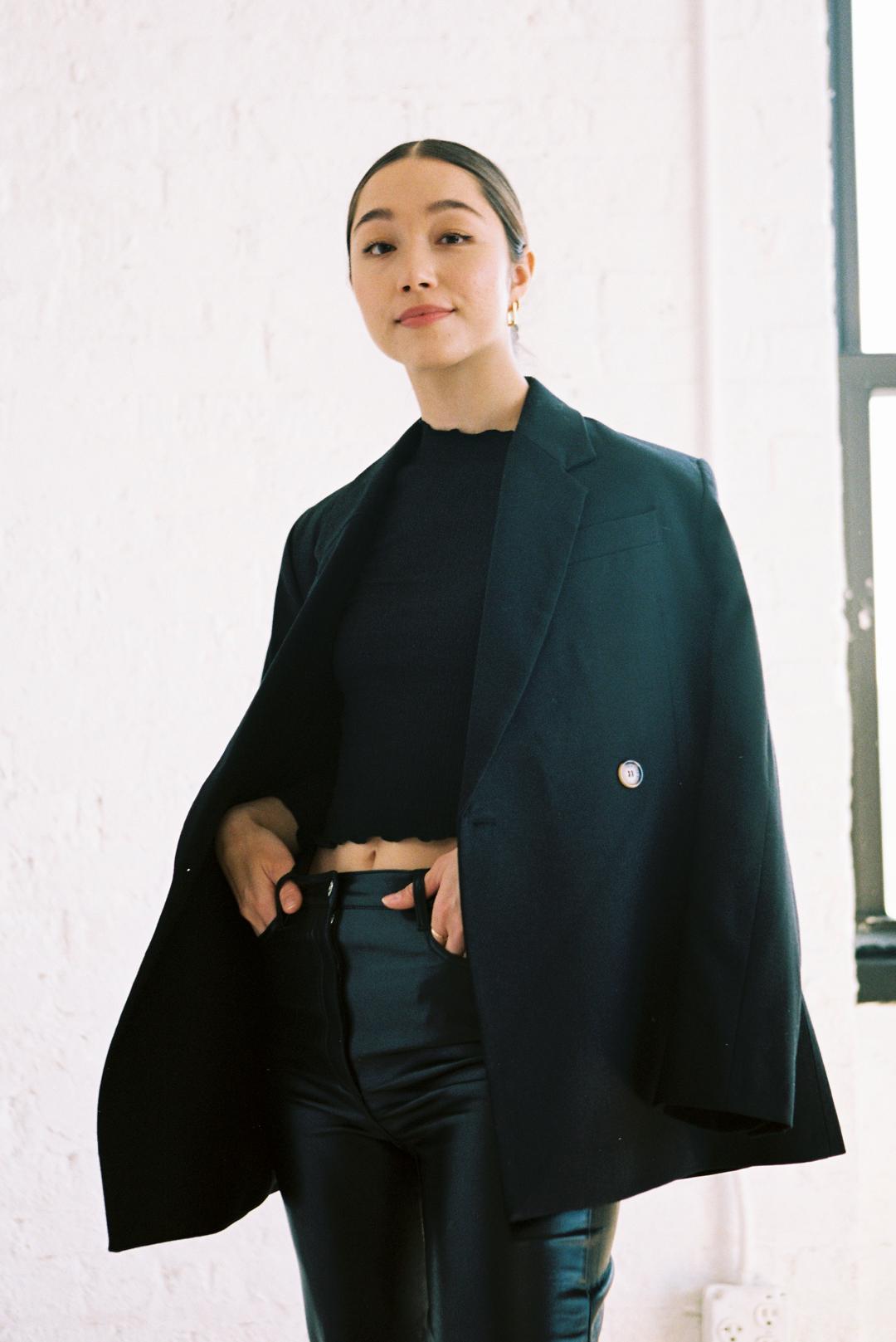 Stephanie Hon, the Founder and CEO of Cadence, standing confidently in a black blazer and pants in front of a window