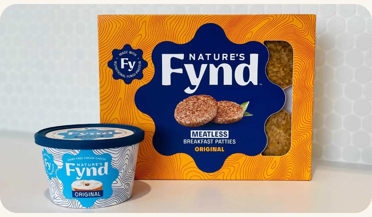 A container of Nature's Fynd, a nutritious fungi protein product, alongside a box of their meatless breakfast patties, representing a sustainable and tasty alternative to traditional meat and dairy products.