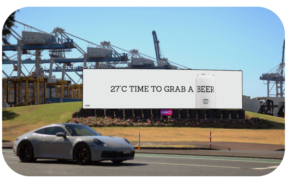 A digital billboard displaying a message '27 c time to grab a beer', indicating it's a perfect time for a refreshing beer due to the warm weather.