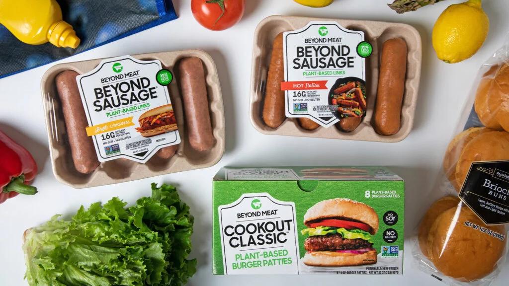 A collection of Beyond Meat products, including burgers and sausages, displayed on a table, representing plant-based food options in the consumer packaged goods industry.