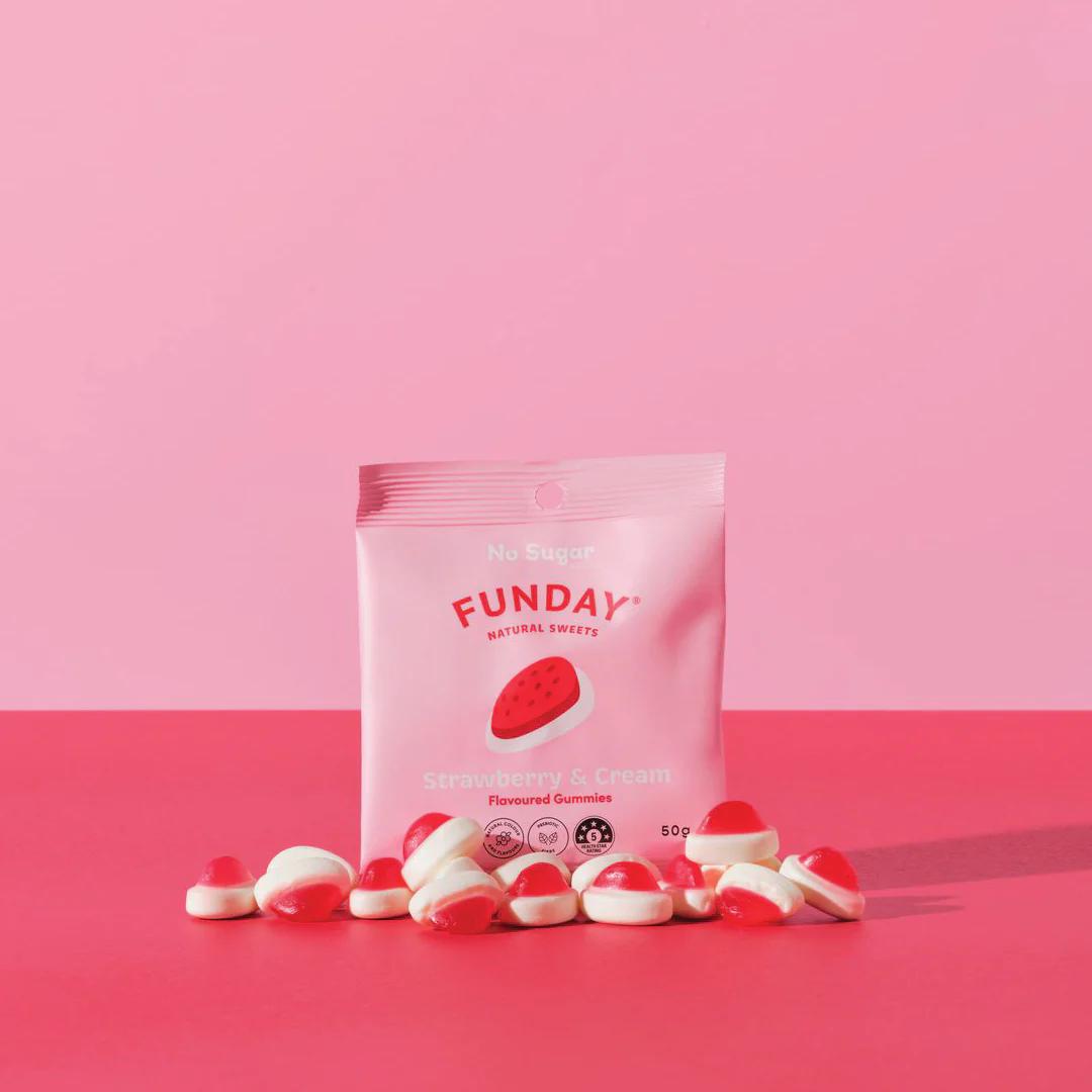 A bag of FUNDAY's strawberry and cream flavored gummies, a healthier confectionery option with natural ingredients, on a pink table.