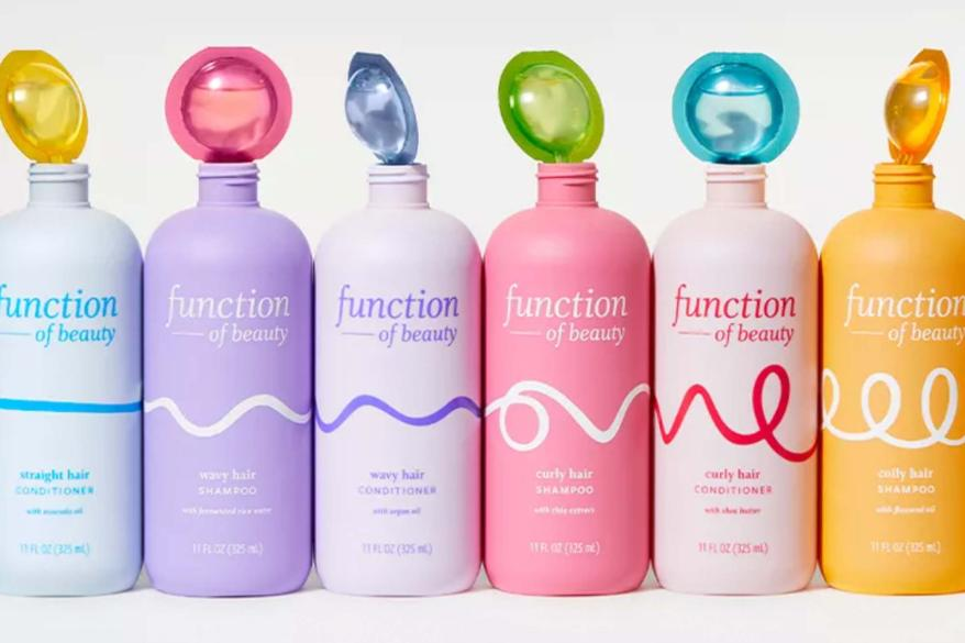 Five bottles of Function of Beauty's personalized hair care products lined up in a row, representing the brand's commitment to customization and eco-friendly practices in the hair care industry
